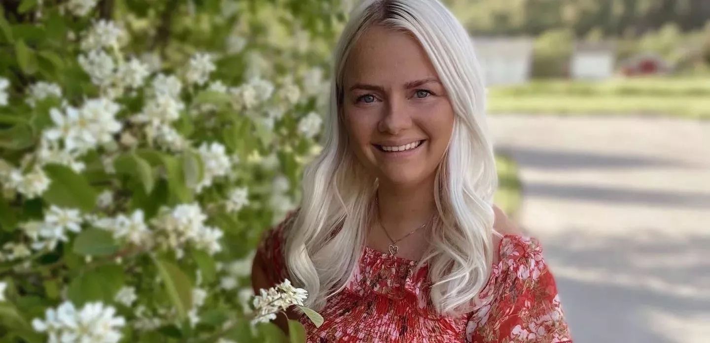 Ruskettunut nainen istuu kalliolla lähellä vuoristomaisemaa.
